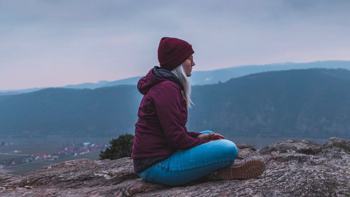 Woman sitting on a rock, enjoying the serene mountain view.